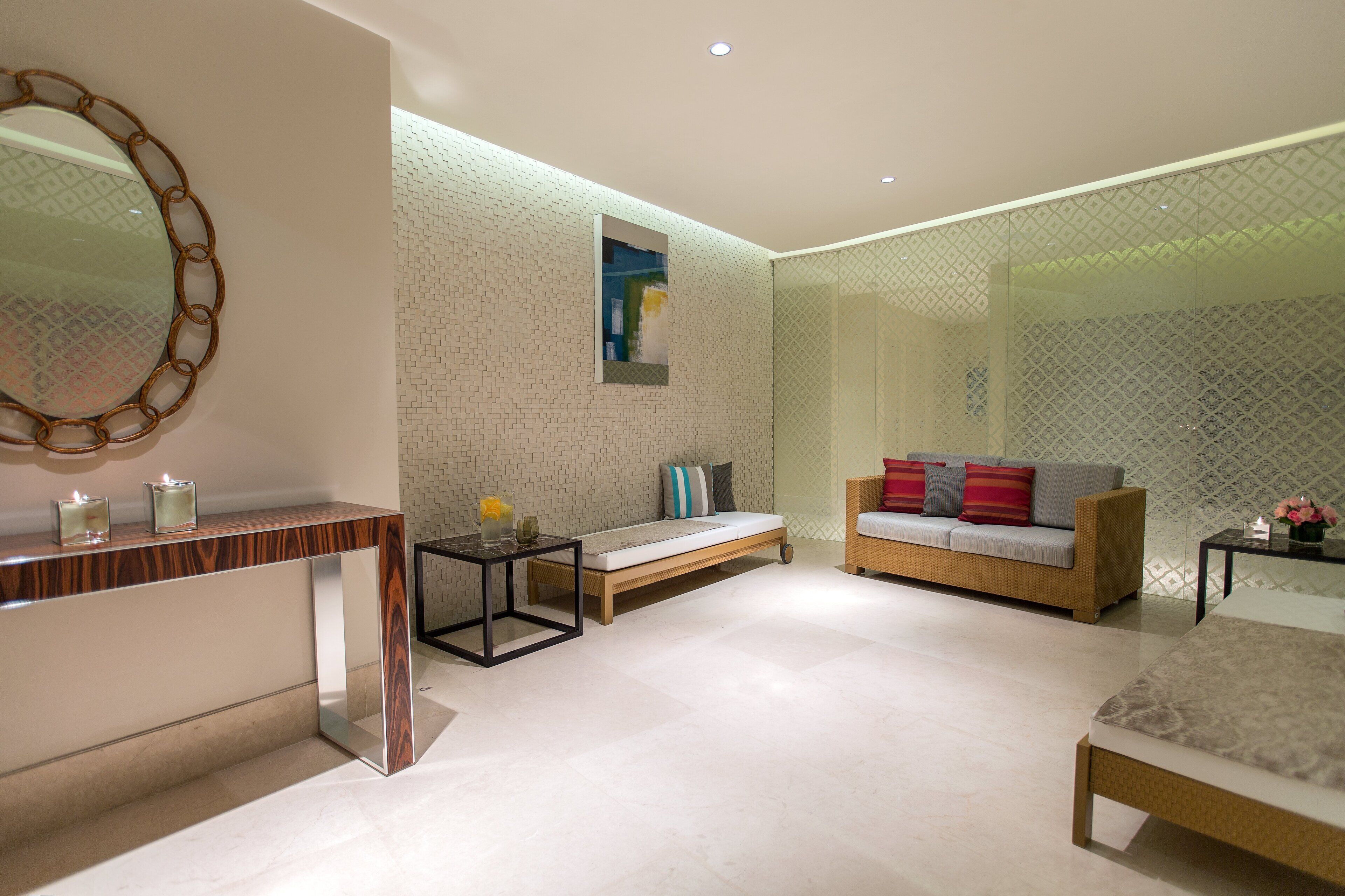 A modern bedroom with a large bed, a sofa, a small table, and a mirror.