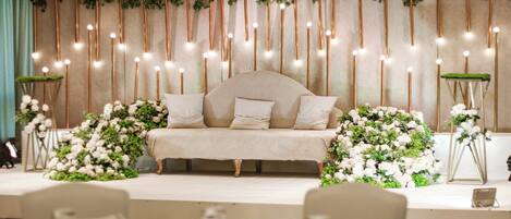 A stage with a sofa, floral arrangements, and vertical light fixtures.