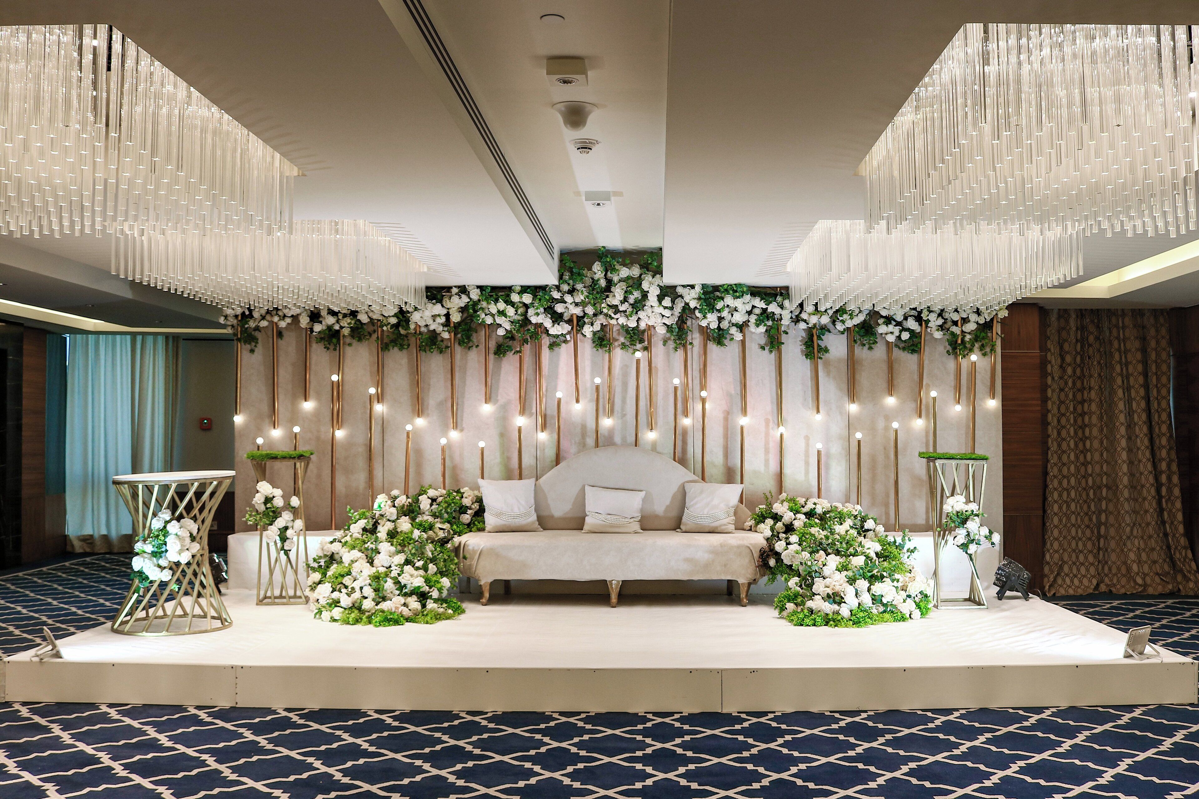 A stage with a sofa, floral arrangements, and a chandelier.