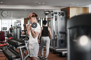 A gym with various exercise equipment and a clock on the wall.