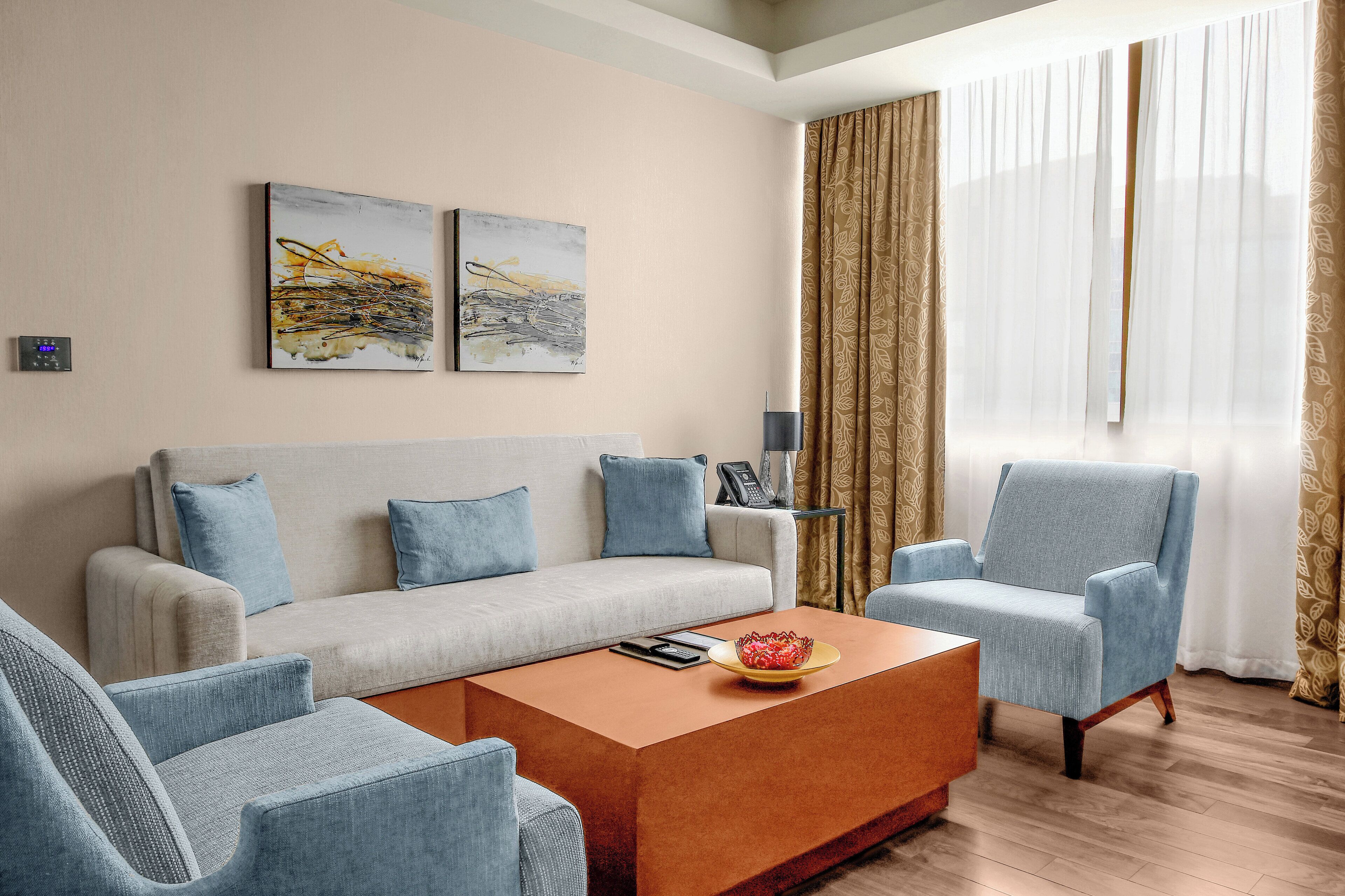 A modern living room with a sofa, two armchairs, a coffee table, and artwork on the wall.