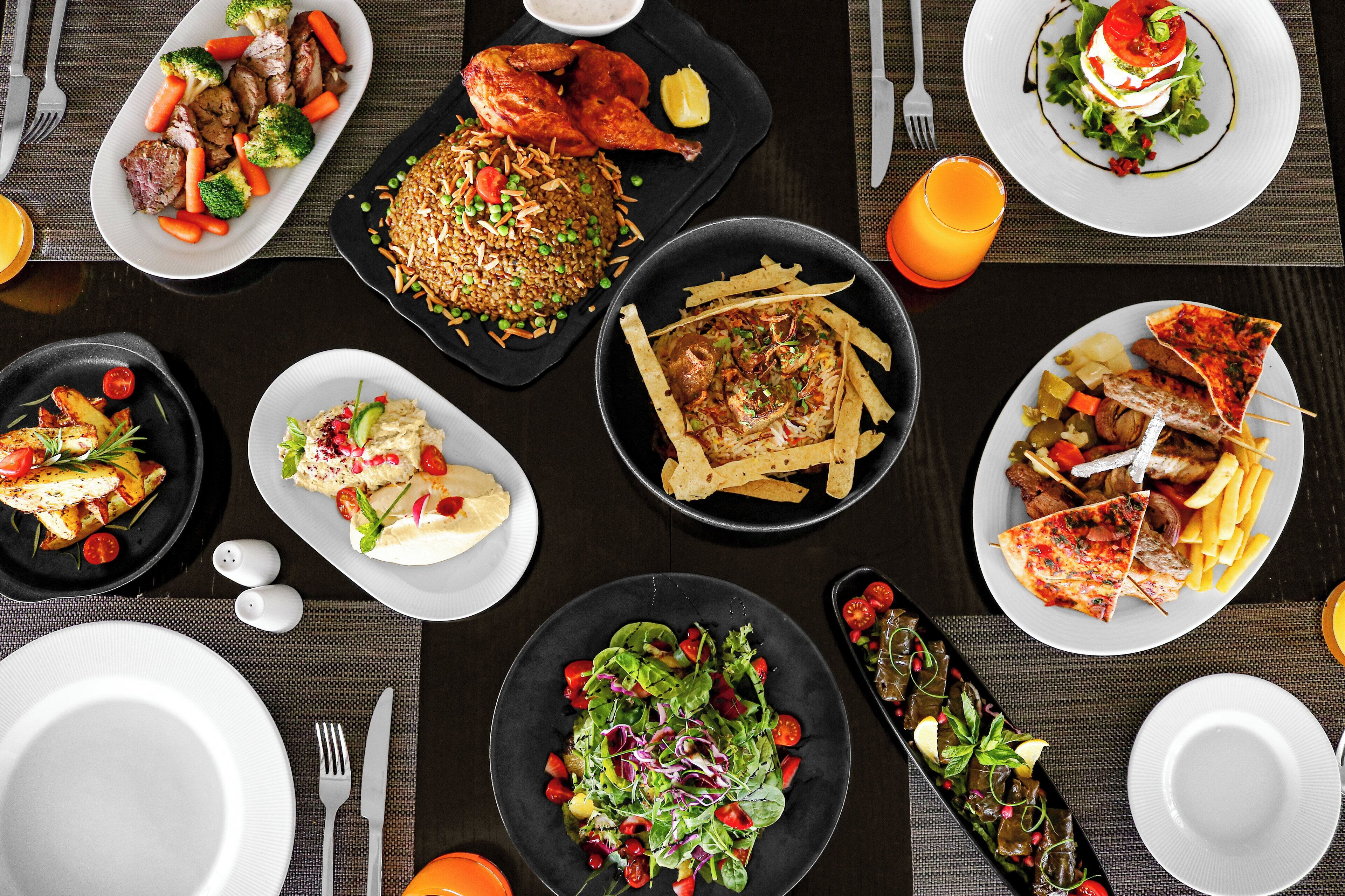 A variety of dishes on a table, including rice, chicken, and salads.