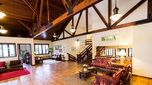 A spacious hotel lobby with a high wooden ceiling, a staircase, and a seating area with patterned sofas. - Hotel Estância Betânia (Colombo)