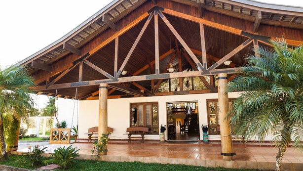 A wooden building with a covered entrance, outdoor seating, and a staircase leading inside. - Hotel Estância Betânia (Colombo)