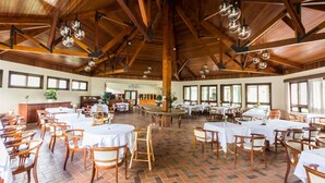 A spacious dining area with high wooden ceilings and large windows. Tables are set with white tablecloths and wooden chairs. - Hotel Estância Betânia (Colombo)