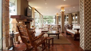 A spacious indoor area with wooden furniture, a fireplace, and a television. - Hotel Estância Betânia (Colombo)