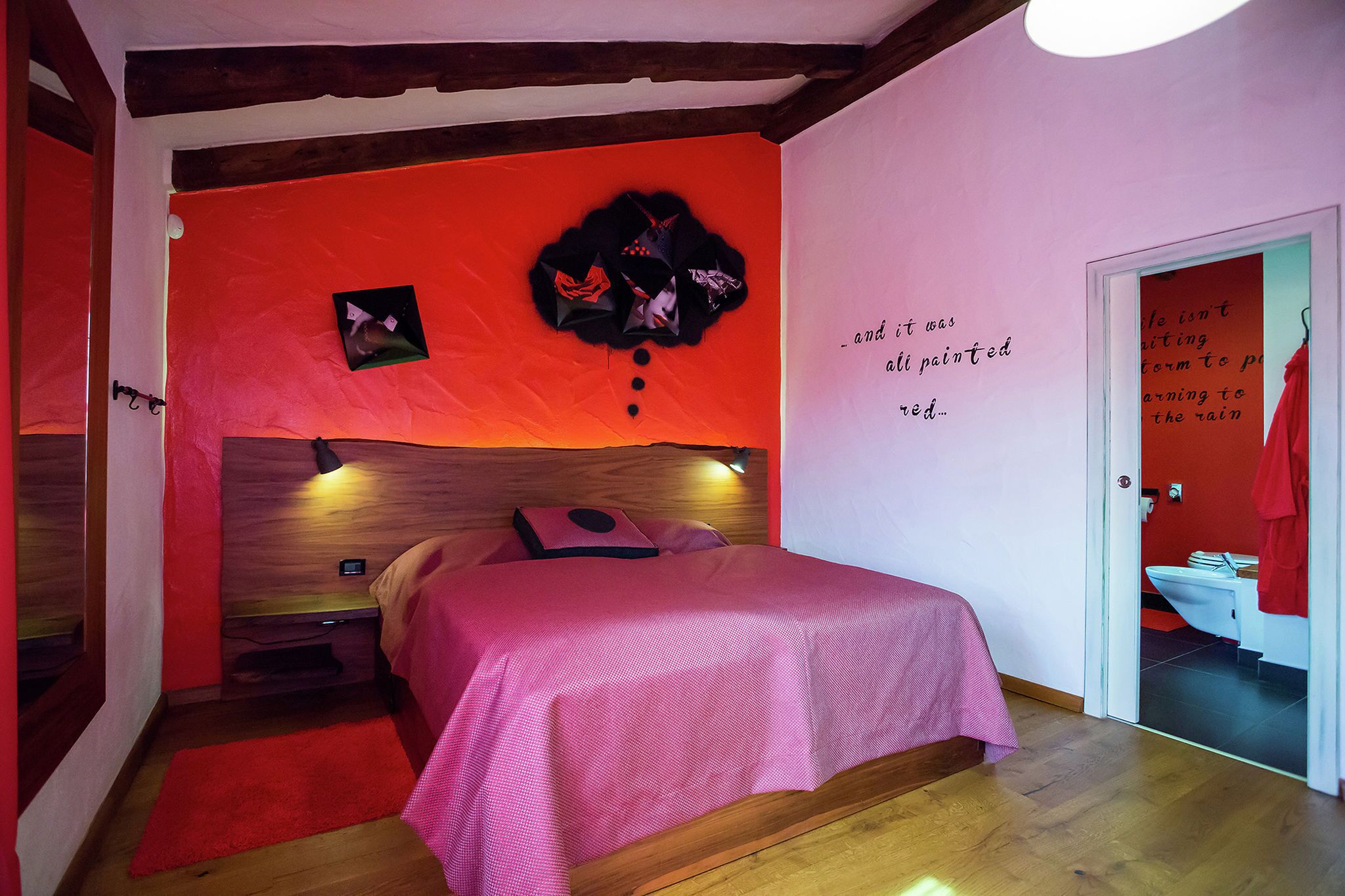 Une chambre à coucher comprenant un lit, une table de chevet, une horloge murale et une porte donnant sur une salle de bain.
