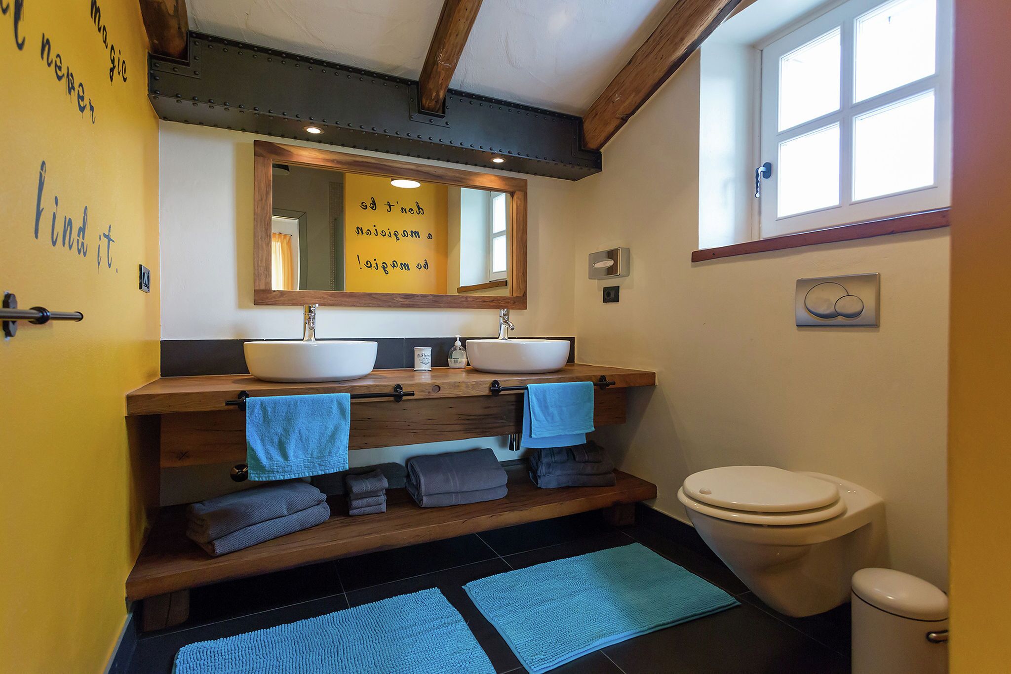 A bathroom with two sinks, a toilet, and a window.