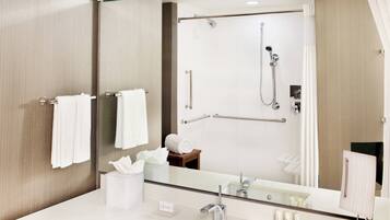 Un baño moderno con cabina de ducha de vidrio, tocador con espejo y perchero para toallas.