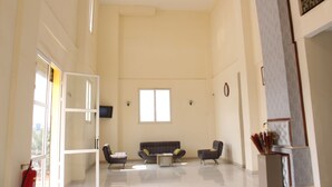 Ampla sala de estar com sofás, uma mesa de centro e uma TV na parede.