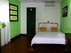 A room with a bed, a green door, and a wall clock. - Hostel Villa Mary (Santa Marta)