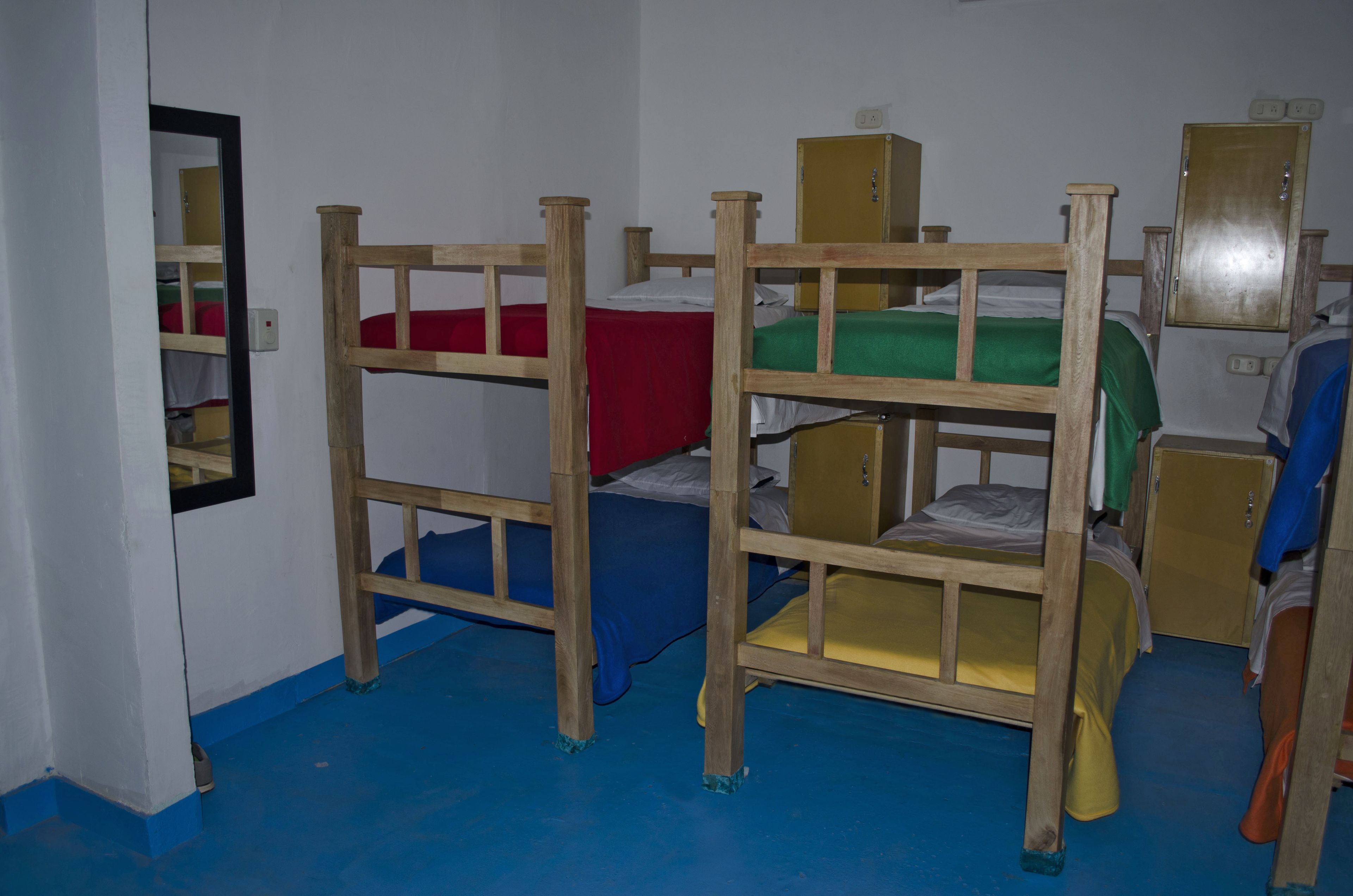 Ein Schlafsaalzimmer mit Etagenbetten, Holzsäcken und einem blauen Boden.
