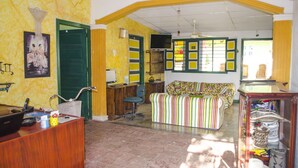 A room with a wooden desk, a green door, a striped sofa, and a display of hats. - Hostel Villa Mary (Santa Marta)