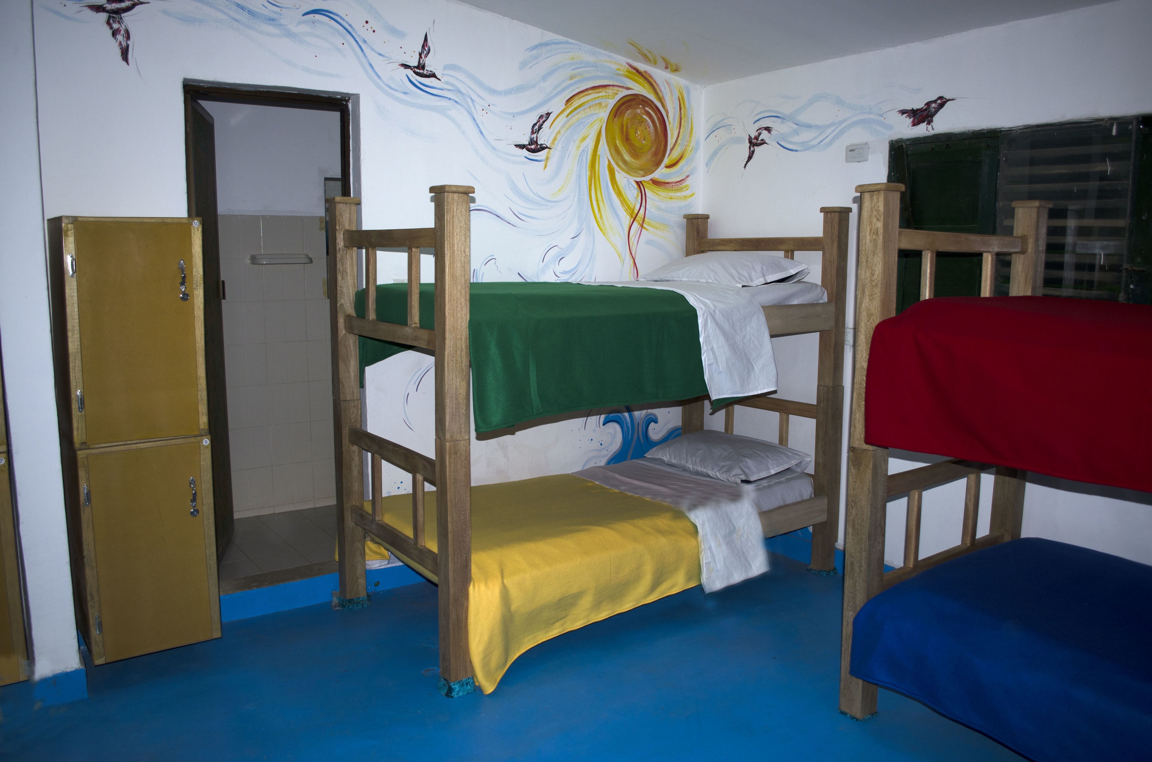 A bunk bed room with a wooden bunk bed, a single bed, and a wardrobe.