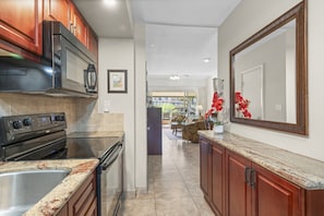 A kitchen with a stove, microwave, and sink, leading to a dining area with a table and chairs.