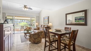 A dining area with a table, chairs, and a ceiling fan. There is a view of a balcony with plants and a sofa. - Maui Kaanapali S #b233 1 Bedroom Condo by RedAwning (Lahaina)