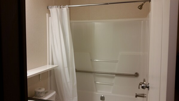 A shower with a glass door, a white curtain, and a towel rack.