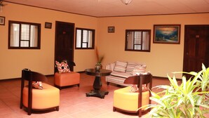 A room with a sofa, two chairs, a table, and a painting on the wall. - Hotel Las Brumas (San Rafael)