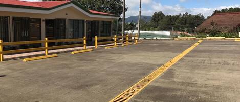 A parking lot with yellow safety lines and a building with a red roof.