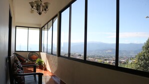A balcony with a view of a cityscape and mountains. There are two chairs and a potted plant. - Hotel Las Brumas (San Rafael)