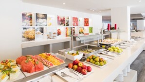 A buffet with various fruits and vegetables displayed on trays. - Arena Beach (La Oliva)