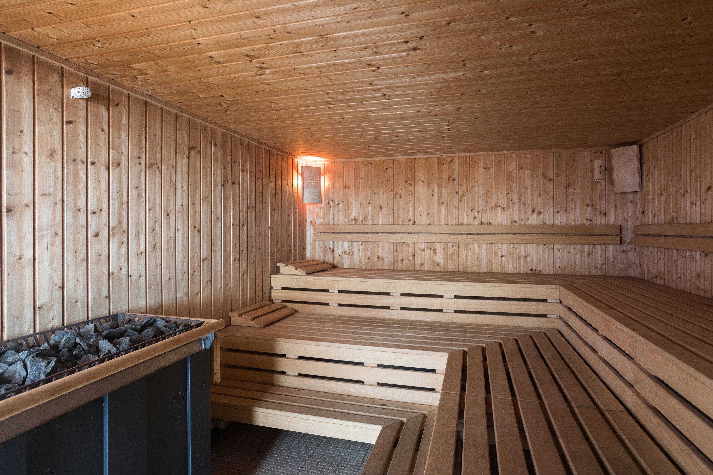 A sauna with wooden benches and a charcoal stove.