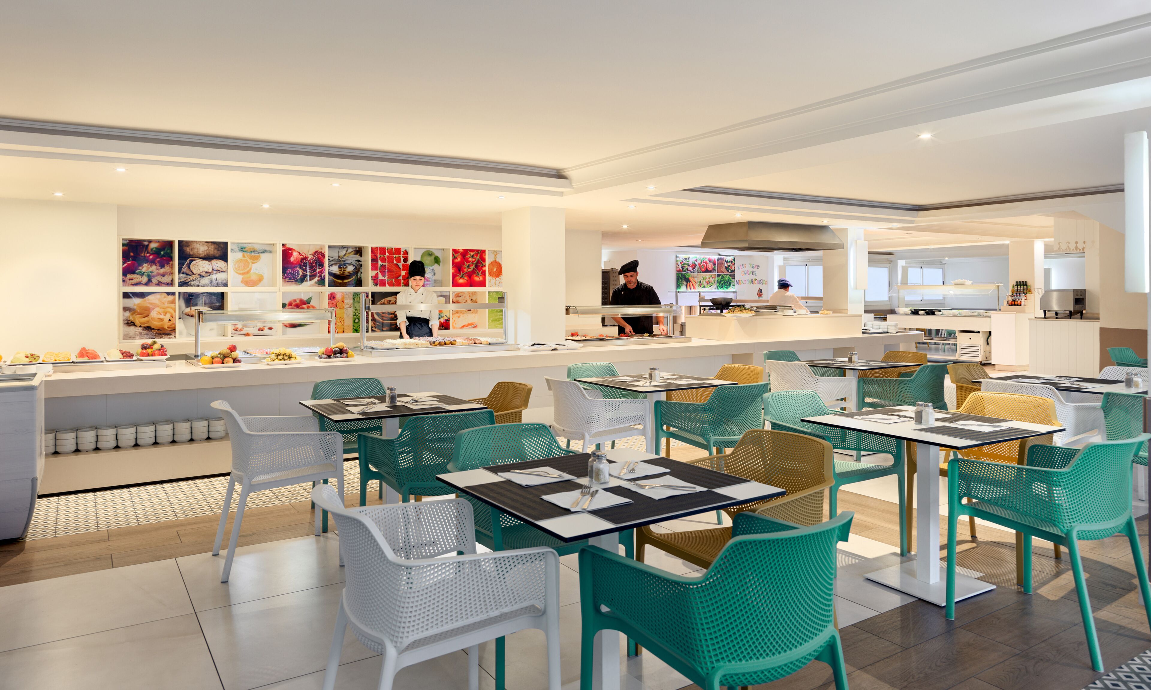 A modern restaurant with a buffet area, colorful food displays, and a variety of seating options including tables and chairs.