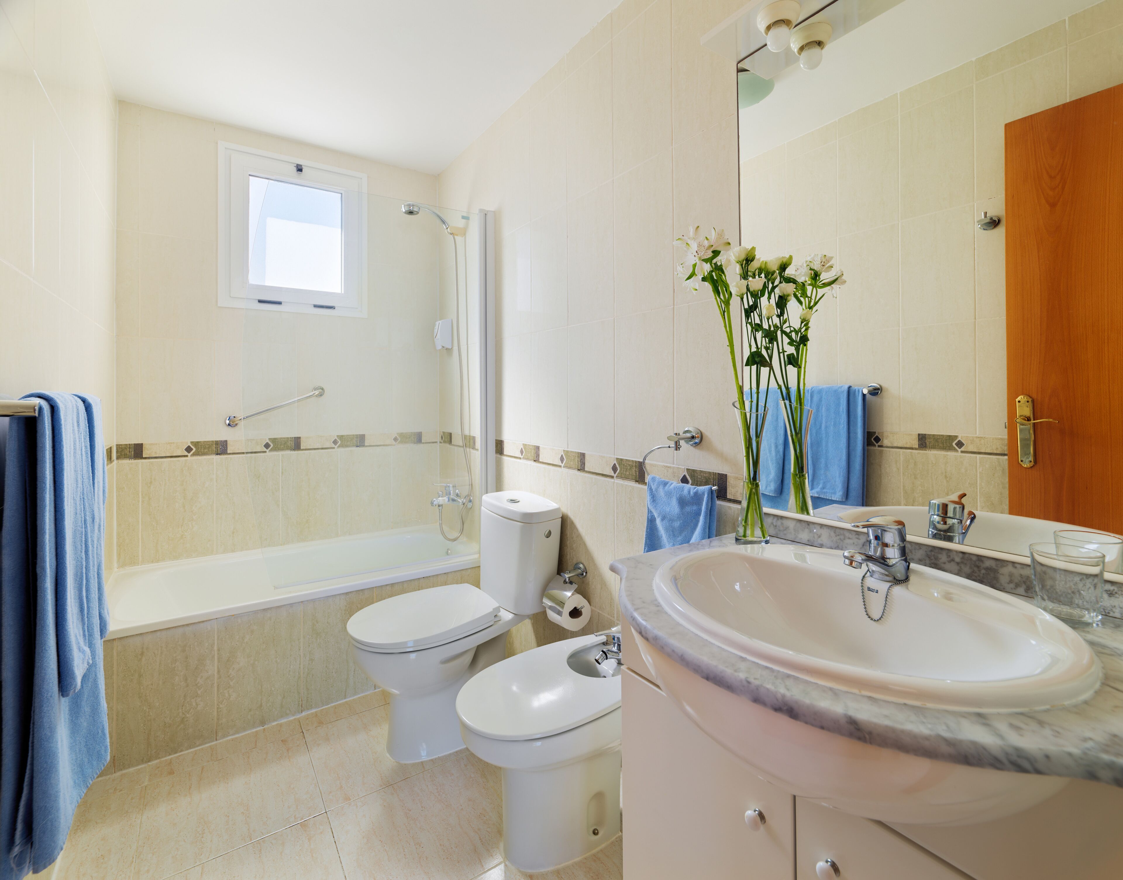 A modern bathroom with a bathtub, two toilets, a sink, and a shower.