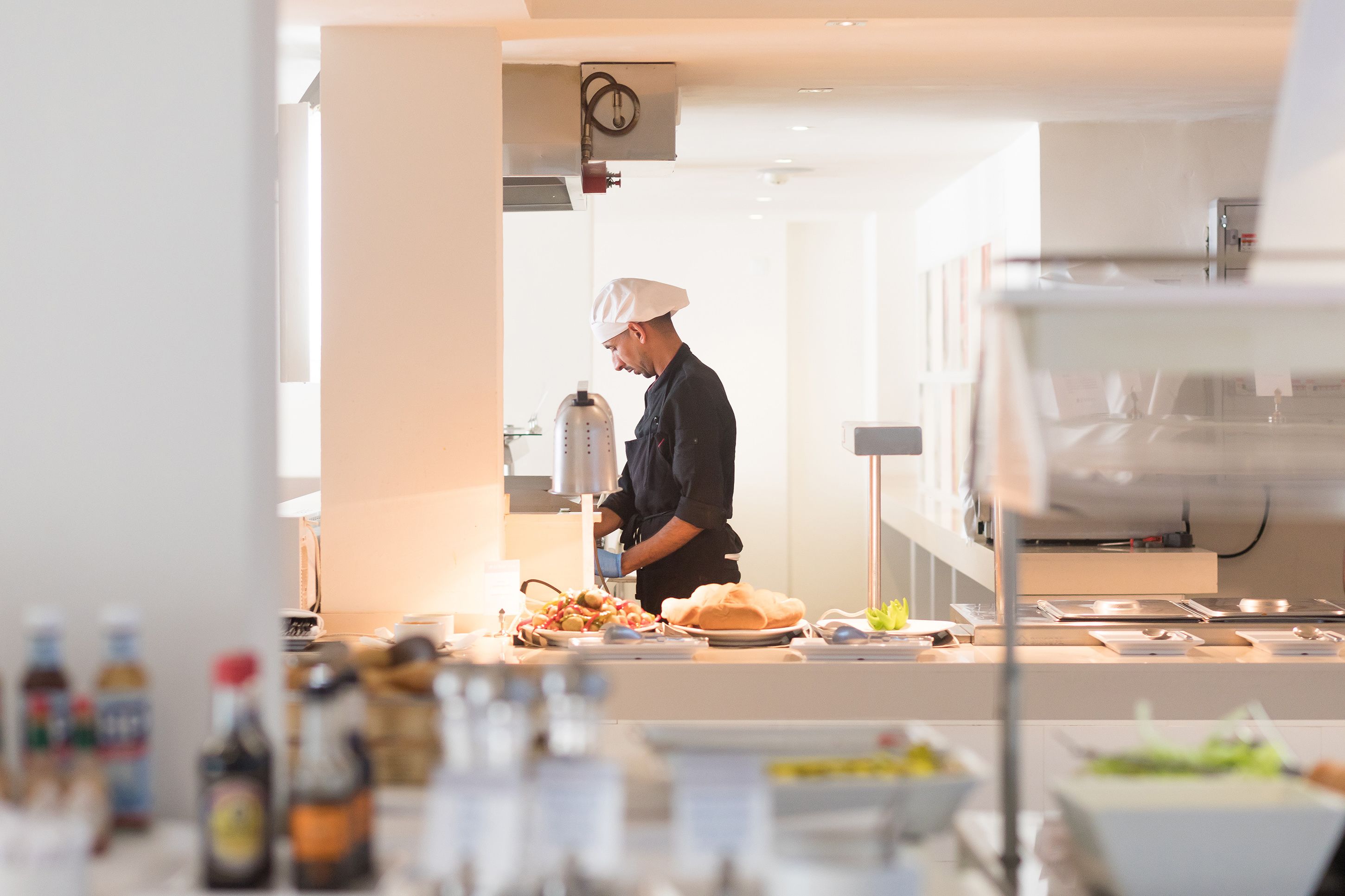 A chef preparing food in a modern kitchen with stainless steel appliances and a clean, organized layout.
