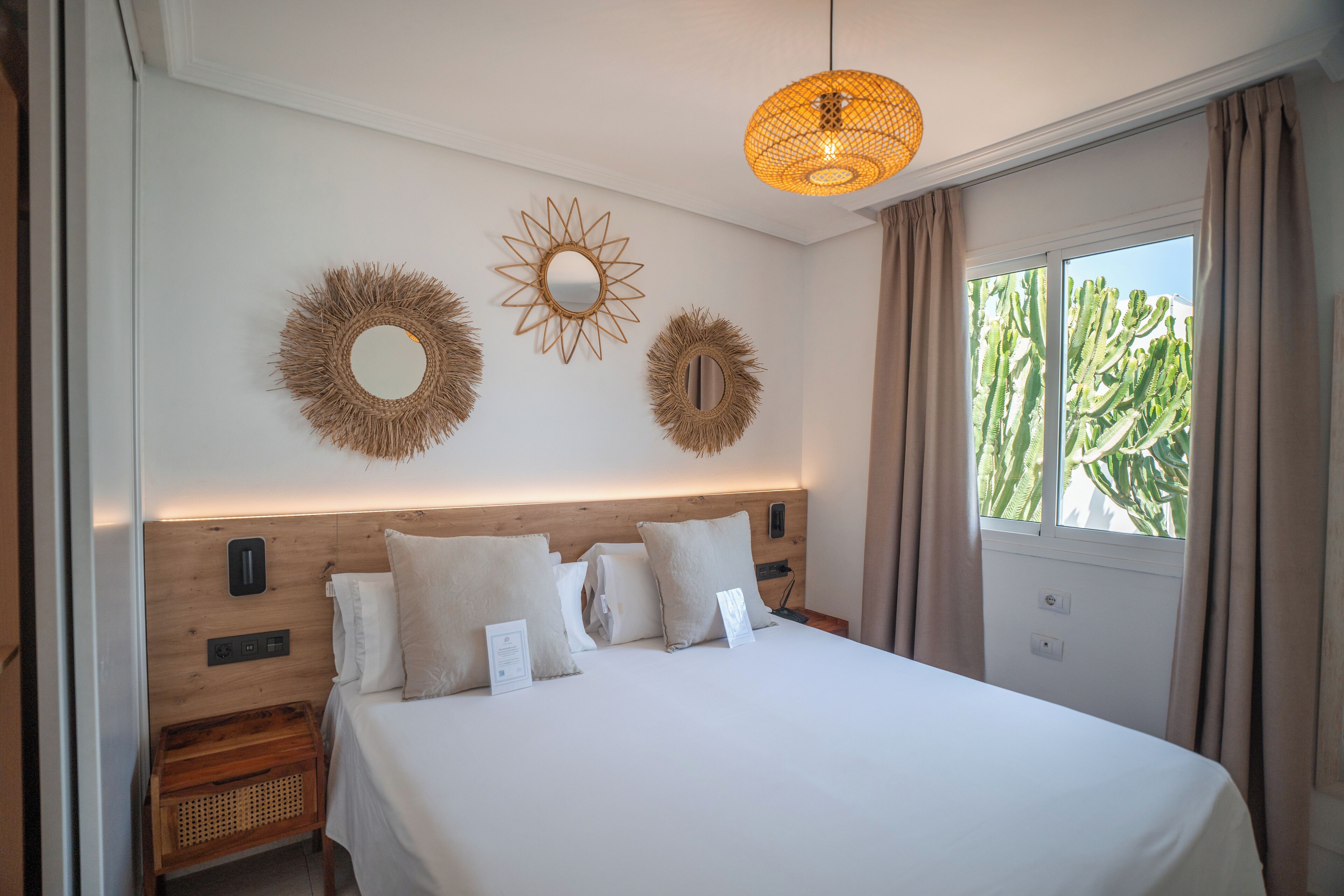 Un lit bien fait, avec une tête de lit, une table de chevet et une lampe fixée au mur.