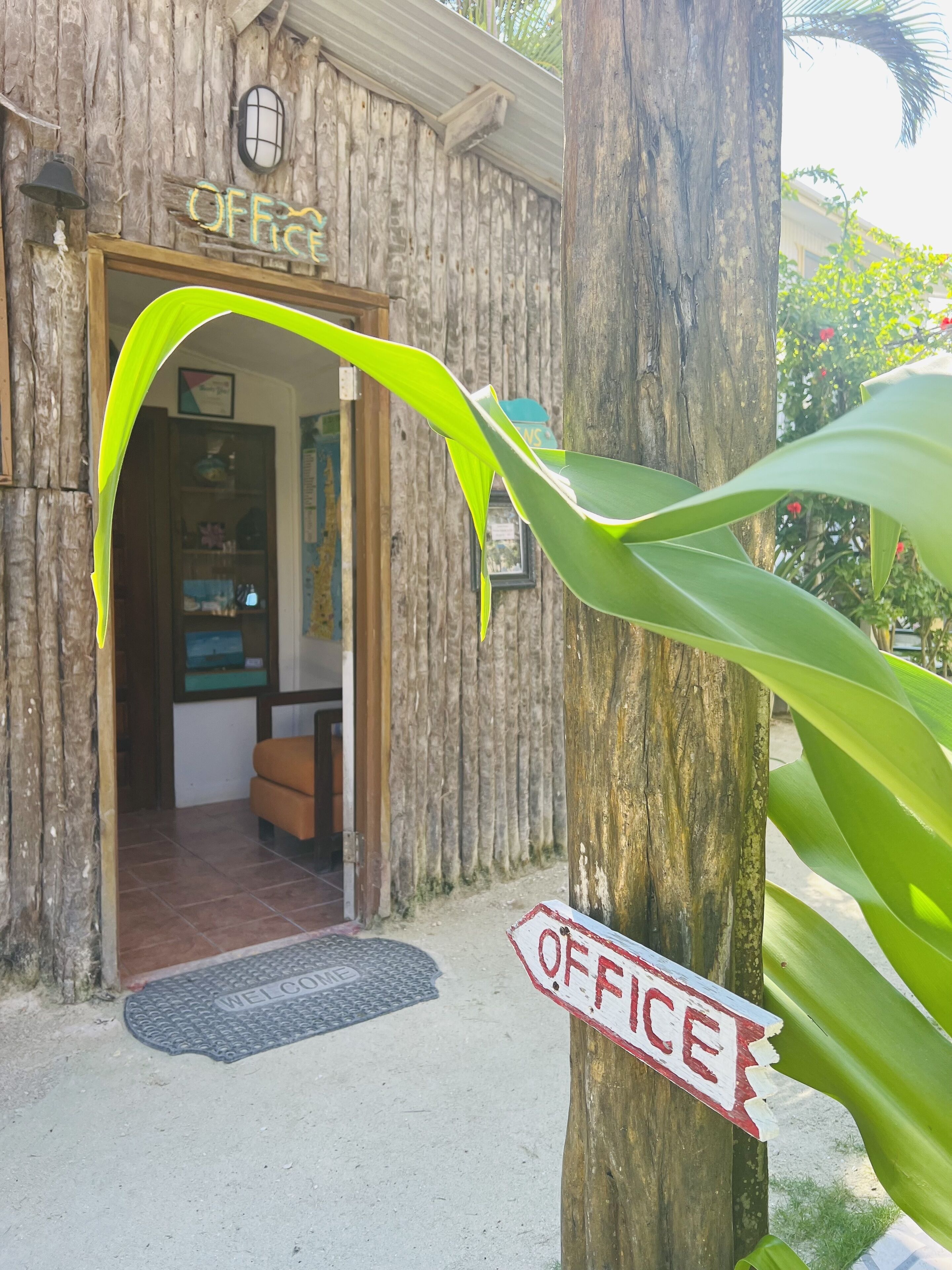 A wooden building with a sign reading "OFFICE" and a welcome mat at the entrance.