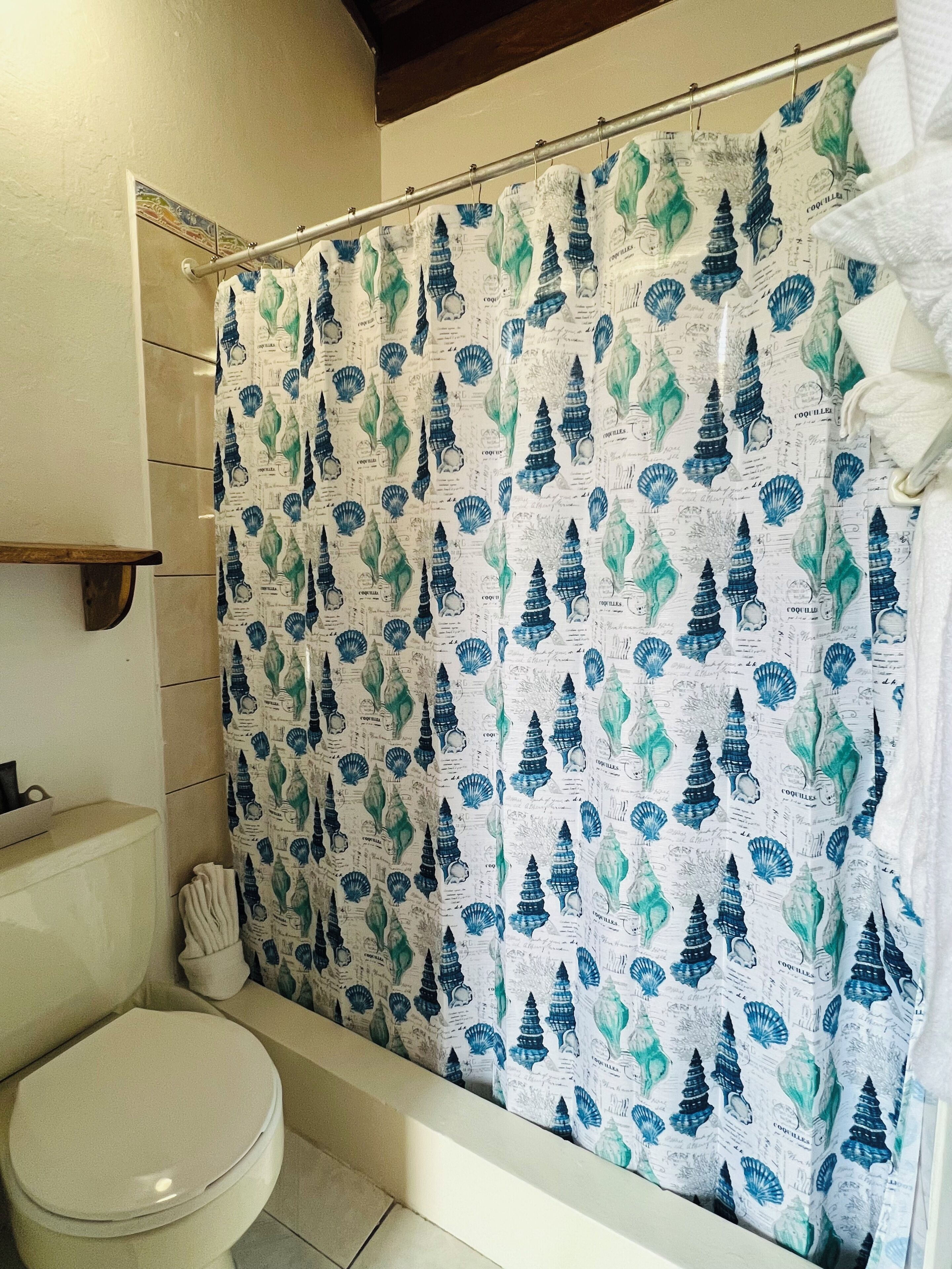 A bathroom with a shower curtain featuring a nautical theme, a toilet, and a bathtub.