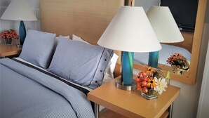 A hotel room with a neatly made bed, two bedside lamps, a mirror, and a small table with a vase of flowers. - Gannett Peak Lodge (Pinedale)