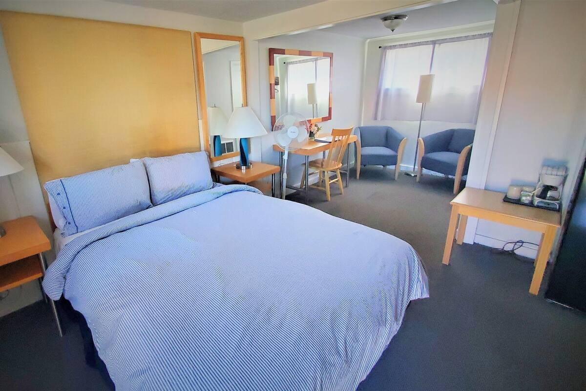 Habitación de hotel con una cama grande, un escritorio con silla, una mesita pequeña y un sofá.