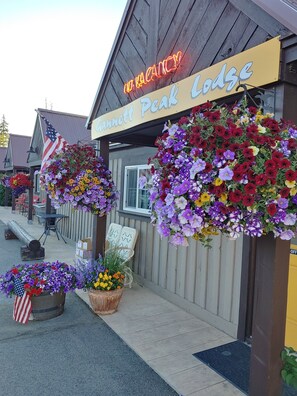 Ein Hotel namens "Hannett Peak Lodge" mit einer Neonreklame, die freie Zimmer anzeigt. Blumenarrangements und eine amerikanische Flagge sind sichtbar.