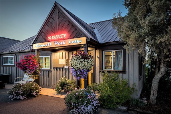A building with a sign reading "Gannett Peak Lodge" and a neon sign above stating "NO VACANCY".