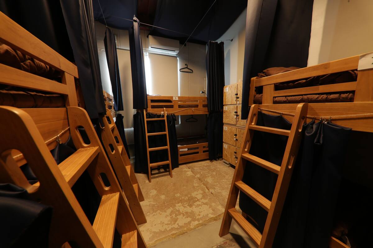 Une chambre de dortoir avec des lits superposés, une armoire et une fenêtre.