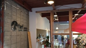Interior de un restaurante con paredes de ladrillo, vigas de madera y un ventanal que da al exterior.