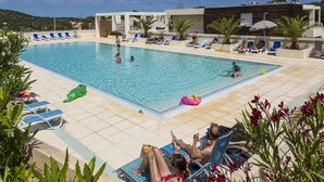 Un área de piscina con sillones de descanso y una piscina azul cristalina.