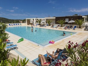 Ein Poolbereich mit Liegestühlen und einem klaren, blauen Pool.