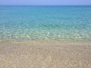 A clear beach with shallow water and a sandy shore.