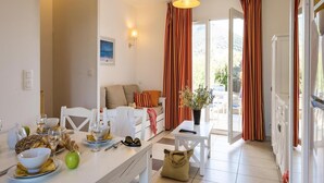 Un comedor con una mesa dispuesta para dos personas, un sofá y vistas al exterior.
