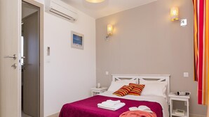 Una habitación de hotel con cama, mesita de noche, lámpara de pared y puerta.