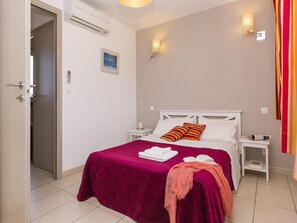 Ein Hotelzimmer mit einem Bett, einem Nachttisch, einer Wandlampe und einer Tür.