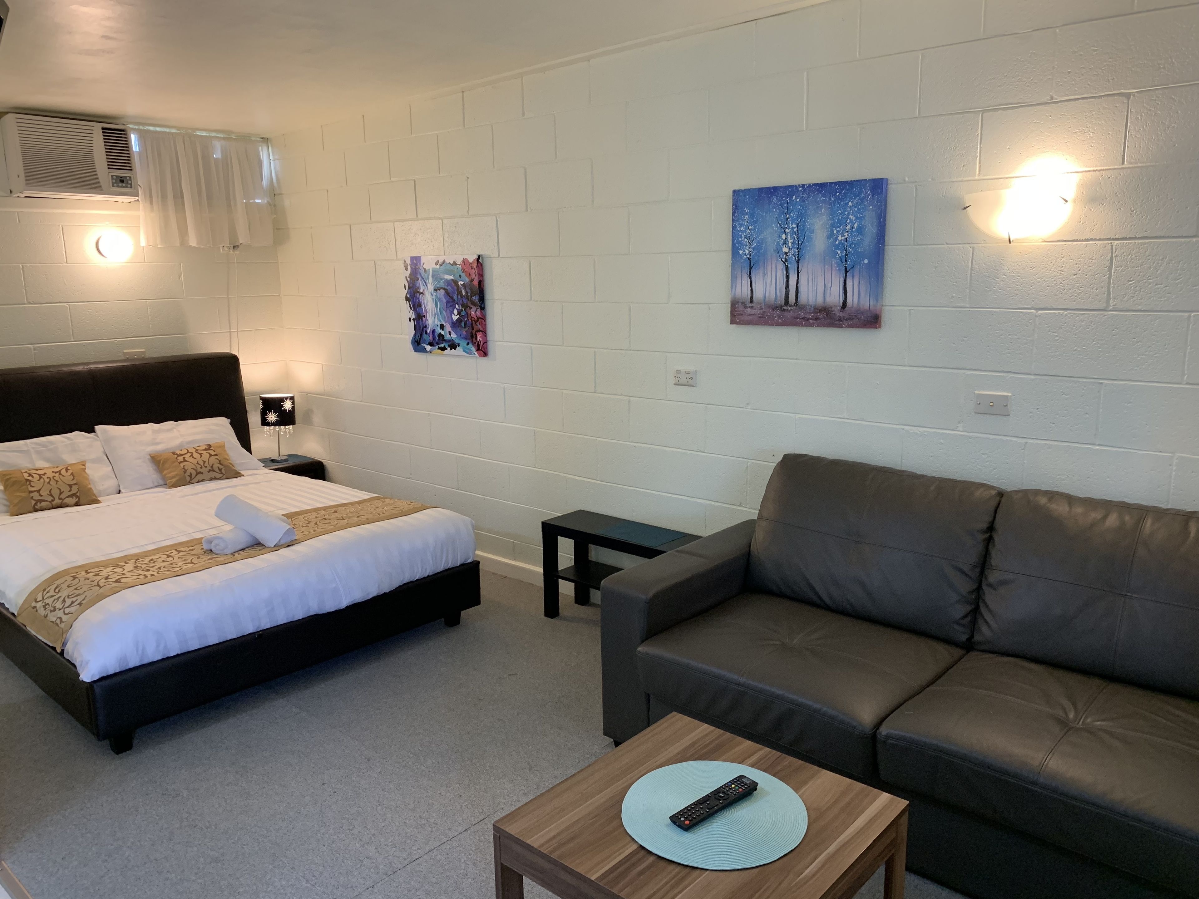 Een hotelkamer met een bed, een sofa, een tafeltje en kunstwerken aan de wanden.