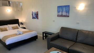 Een hotelkamer met een bed, een sofa, een tafeltje en kunstwerken aan de wanden.