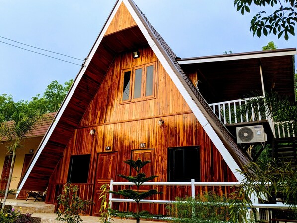 A wooden house with a triangular roof, numbered rooms, and an air conditioning unit. - Bansuanphuhong (Chiang Khan)