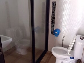 A bathroom with a toilet, a bidet, and a glass shower enclosure. - Bansuanphuhong (Chiang Khan)