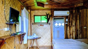 A compact room with a bed, a small table with towels, a mounted TV, and an air conditioning unit. - Bansuanphuhong (Chiang Khan)