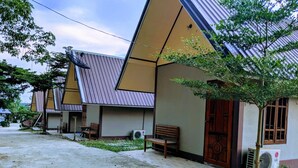 A row of buildings with a sloped roof, outdoor seating, and air conditioning units. - Bansuanphuhong (Chiang Khan)